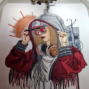 Op de afbeelding: Geborduurd kunstwerk van een persoon met een rode hoodie, zonnebril en koptelefoon. Het ontwerp toont een zonsopgang en een stadsgezicht. De borduurwerk is gedetailleerd met verschillende kleuren en texturen.