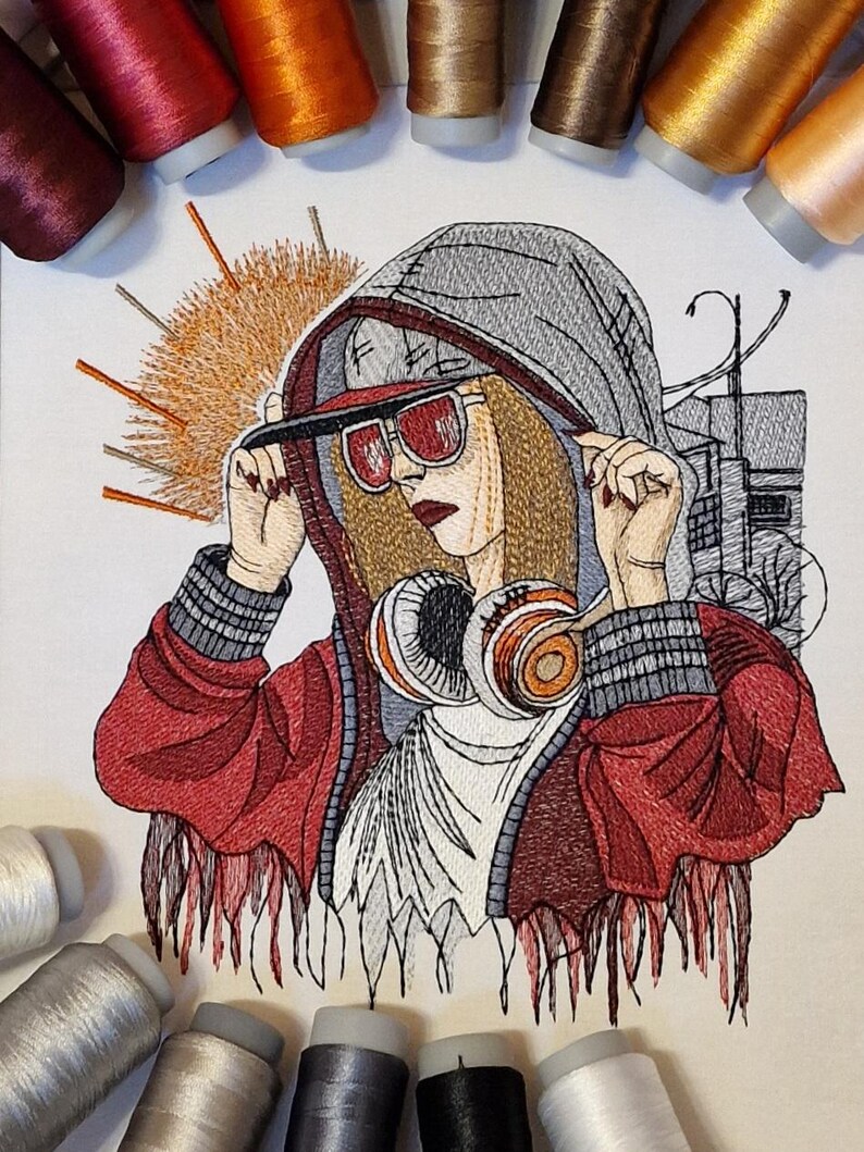 Op de afbeelding: Geborduurd kunstwerk met een persoon in een rode jas, grijze hoodie en zonnebril, met een koptelefoon. Het kunstwerk is omgeven door spoelen kleurrijk garen, wat duidt op een knutselproject. De stijl is gedetailleerd.