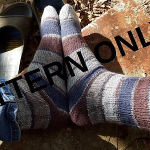Puede incluir: Un par de calcetines a rayas en tonos grises, azules y marrones. Los calcetines están usados y el patrón es visible. Los calcetines los lleva puestos una persona sentada en una roca.