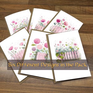 May include: Six greeting cards with floral designs in watercolour. Each card shows a different arrangement of pink flowers, a pink picket fence, and greenery. The cards have a white interior and a brown border. Text on the image reads "Six Different Designs in the Pack."