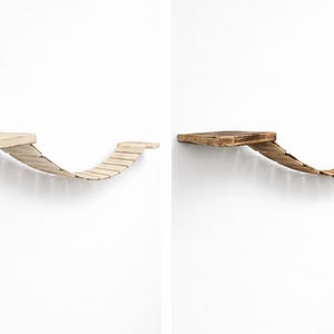 Può includere: Due mensole in legno per gatti, una chiara e una scura, montate su una parete bianca. Ogni mensola presenta una piattaforma rettangolare collegata a un ponte curvo a doghe, creando una struttura per l'arrampicata per animali domestici.