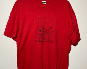 May include: Red t-shirt with a black graphic of a group of people singing with the text "United We Sing" and "A Celebration of Music".