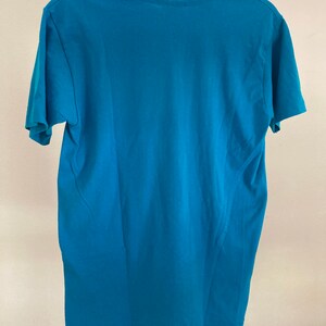 May include: A teal blue short-sleeved t-shirt with a crew neck.