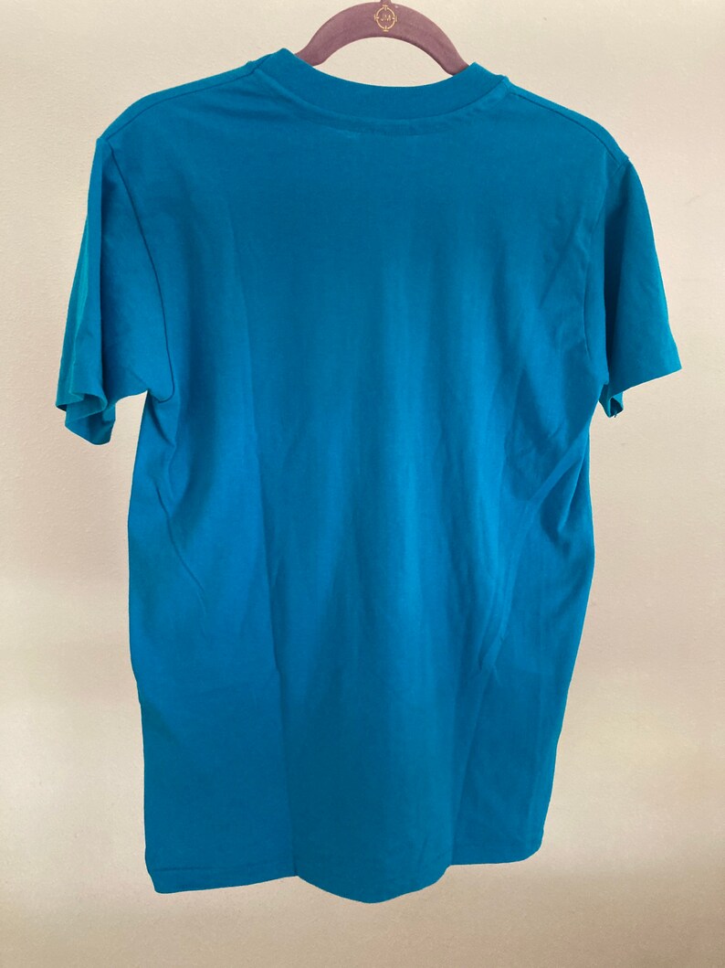 May include: A teal blue short-sleeved t-shirt with a crew neck.