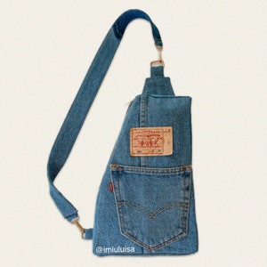 May include: A blue denim crossbody bag with a zipper closure and a Levi's patch. The bag has a back pocket and a front pocket. The bag is made from recycled denim.