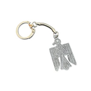 May include: Silver-coloured metal keyring featuring a stylised Thunderbird design. The keyring has a circular ring and a flexible connecting chain. The Thunderbird has a detailed, textured pattern, with a bird-like head and outstretched wings. The background is white.