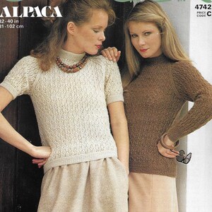 May include: Two women in knitwear. One wears a cream-coloured, short-sleeved sweater with a textured pattern, paired with a beige skirt. The other wears a brown, long-sleeved sweater and a light peach skirt. The image includes the text "ALPACA" and size information: 32-40 in (81-102 cm).
