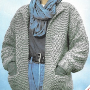 May include: A grey knitted cardigan with pockets and a shawl collar. The cardigan is being worn by a woman with short, curly hair. The text on the image reads "3829 SNOWBALL 81-112 cm 32-44 in Seven sizes".