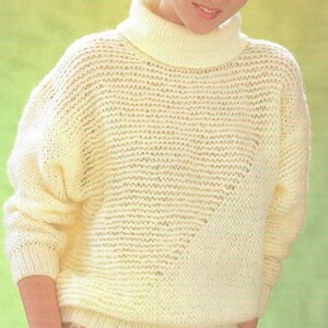 May include: A white knitted jumper with a turtleneck and a loose fit. The jumper has a delicate open stitch pattern.
