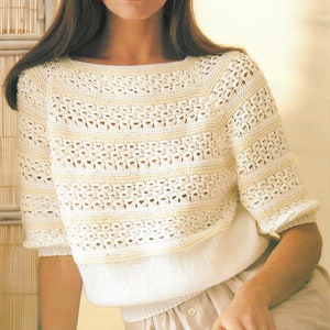 May include: A white crocheted sweater with a delicate openwork pattern. The sweater has a round neckline and short sleeves. The model is wearing the sweater with a beige skirt. The text on the image reads "1535 Sunbeam 1st Edition DK and Elysee Ribbon 76-102 cm 30-40 ins."