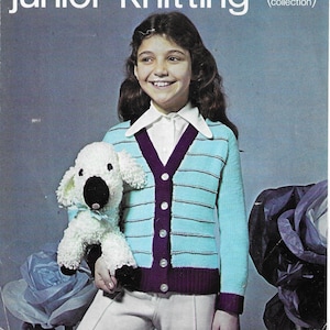 May include: A vintage magazine cover for "Lister / Lee Target junior knitting." The cover features a smiling girl wearing a blue and purple striped cardigan and holding a white stuffed dog. The text includes chest measurements in inches and centimeters.