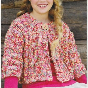 Peut inclure: Un cardigan tricoté épais et coloré, aux tons de rouge, rose, jaune et bleu. Le gilet ouvert est orné d'un gros bouton en bois. Les manches longues et le style général évoquent le confort et le fait main.