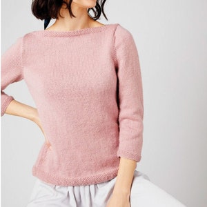 Könnte beinhalten: Ein weicher rosa Strickpullover mit einem Boot Ausschnitt und Dreiviertelärmeln.