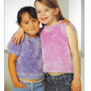 Puede incluir: Dos chicas con tops de punto peludos. La chica de la izquierda lleva un top morado de manga corta y la chica de la derecha lleva un top rosa sin mangas. Ambas chicas llevan pantalones vaqueros azules. La imagen incluye el texto "Eskimo DK" y "Stylecraft".