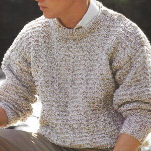 Puede incluir: Un su&eacute;ter de punto beige y blanco con cuello redondo y detalles de botones en los hombros.