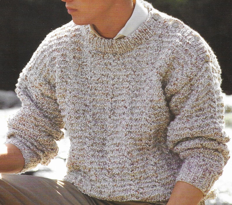 Puede incluir: Un su&eacute;ter de punto beige y blanco con cuello redondo y detalles de botones en los hombros.