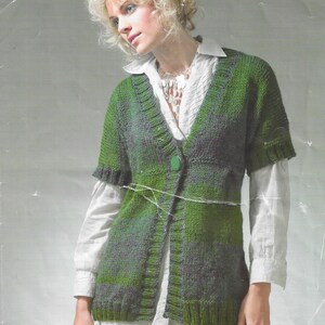 May include: A green and purple chunky knit cardigan with a V-neck and a single button closure. The cardigan has short sleeves and is shown being worn by a model. The text "Phases" and "8439" are visible in the image. The text "Chunky" is also visible in the image.