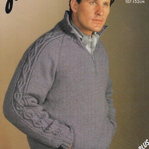 以下が含まれることがあります： 首元にジッパーが付いたグレーのケーブルニットセーター。袖にはケーブルニットの模様が入っています。セーターの前身頃にはポケットが付いており、42インチ以上のサイズです。画像には「JX124 DK 42-60in 107-152cm」というテキストが印刷されています。