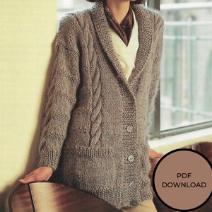 May include: A brown knitted cardigan with a cable knit pattern, a shawl collar, and a button closure. The cardigan has two pockets and is shown being worn by a person.