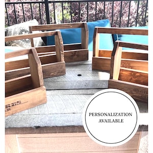 May include: Four dark brown stained wooden caddies with open tops and central carrying handles. Each caddy features a rectangular base and side panels. One caddy displays partial text, and a circular white graphic reads PERSONALIZATION AVAILABLE.