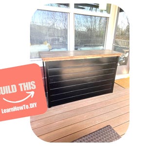 May include: A rectangular bar counter featuring a natural wood-toned top and a black horizontal shiplap base. A coral-colored square graphic overlay on the left side displays the white text BUILD THIS with an arrow and LearnHow.DIY below it.