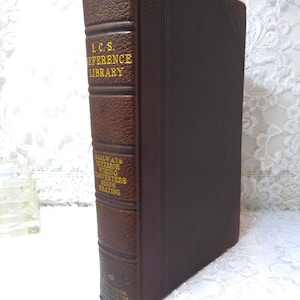 May include: A vintage brown leather-bound book with gold lettering. The spine reads "I.C.S. REFERENCE LIBRARY" and "RAILWAYS INTERIOR WIRING CONVERTERS SIGNS HEATING". The book has a worn appearance.
