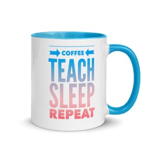 Puede incluir: Taza de café de cerámica blanca con borde y asa azules. La taza tiene un diseño degradado azul y rosa con el texto "Coffee Teach Sleep Repeat".