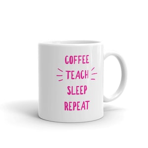 Puede incluir: Taza de café de cerámica blanca con el texto "COFFEE TEACH SLEEP REPEAT" en letras rosas.