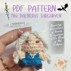 May include: A crochet doll of a character with long white hair, pink cheeks, and a blue outfit. The text reads PDF PATTERN, Mini DAENERYS TARGARYEN, Dracarys!, Daenerys Stormborn of House Targaryen of the blood of Old Valyria, and @loomy.tools.
