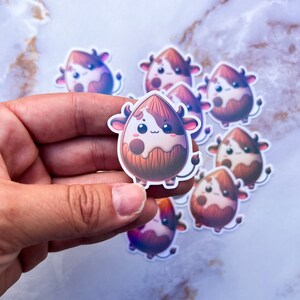 May include: A set of eight brown and white cow-shaped stickers with a milk-filled almond design. The stickers are glossy and have a cartoonish style.