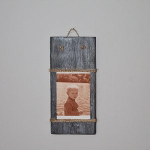May include: A rectangular photo frame crafted from grey-painted wood, featuring a sepia-toned photograph of a child by a lake. The frame is adorned with jute twine and has a twine loop at the top for hanging.