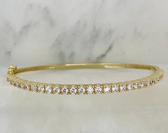 Puede incluir: Un brazalete de oro con una sola fila de piedras de circonita cúbica transparentes.