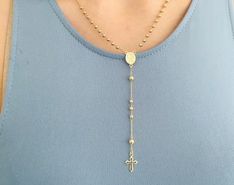 Puede incluir: Un collar de rosario dorado con un colgante redondo y un dije de cruz.