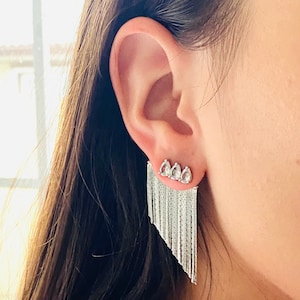 May include: Silver dangle earrings with a fringe of small chains and four clear teardrop-shaped crystals.