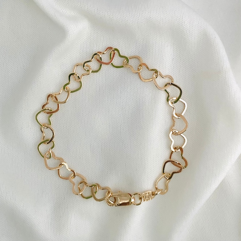 Puede incluir: Un brazalete de cadena dorada en forma de coraz&oacute;n con cierre de langosta.