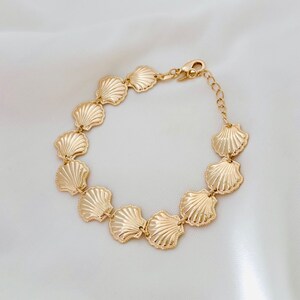 May include: A gold-tone bracelet with a chain link design and a series of connected seashell charms.