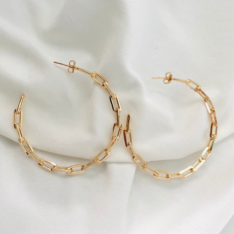 May include: A pair of gold hoop earrings with a chain link design.
