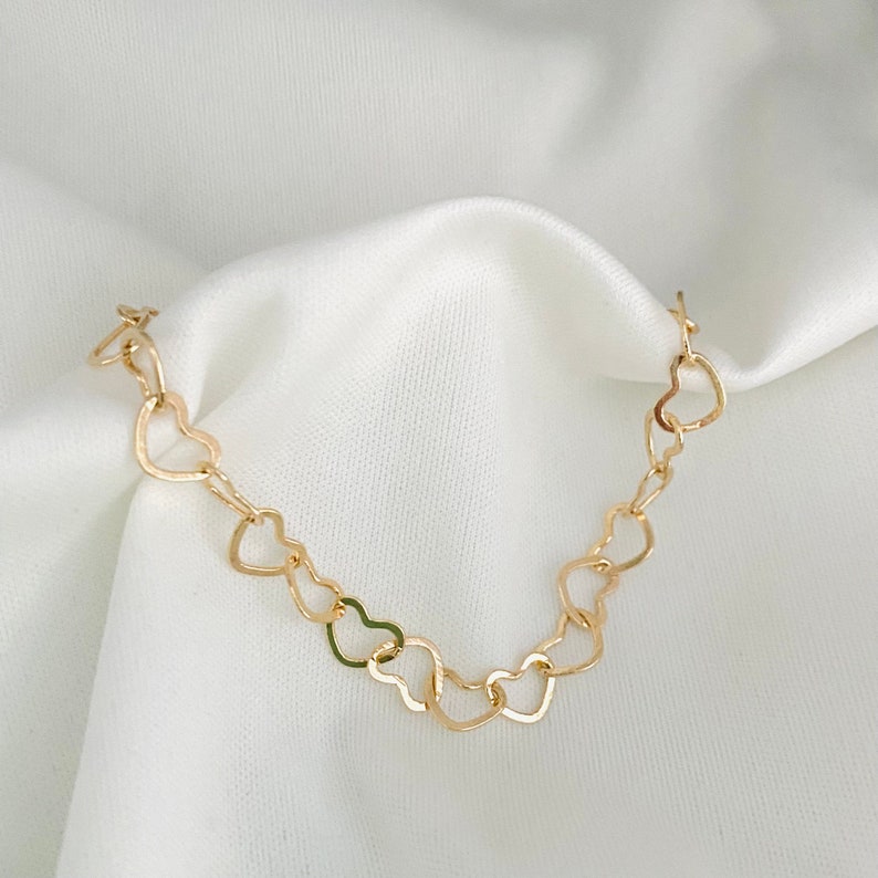Puede incluir: Un collar de oro con una cadena hecha de corazones enlazados.