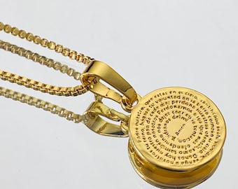 May include: A gold necklace with a round pendant featuring a circular inscription in Spanish. The inscription reads "Padre nuestro que estas en el cielo, santificado sea tu nombre, venga a nosotros tu reino, hágase tu voluntad en la tierra como en el cielo. Danos hoy nuestro pan de cada día, perdona nuestras ofensas, como también nosotros perdonamos a los que nos ofenden. No nos dejes caer en la tentación, mas líbranos del mal. Amen."