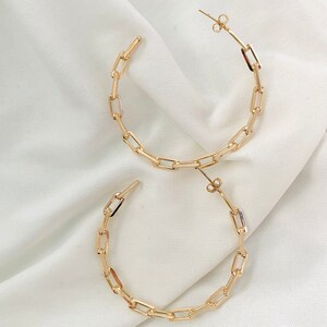 May include: A pair of gold hoop earrings made of linked rectangular shapes.
