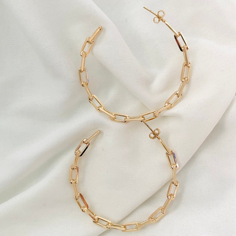 May include: A pair of gold hoop earrings made of linked rectangular shapes.