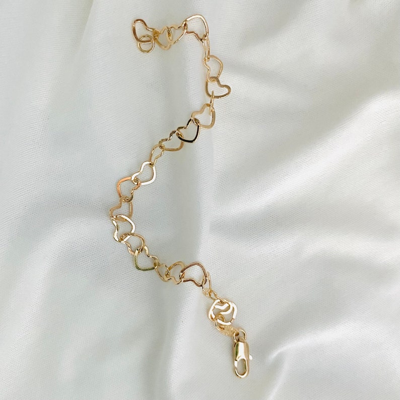Puede incluir: Un brazalete de cadena dorada en forma de coraz&oacute;n con cierre de langosta.
