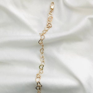 Puede incluir: Un brazalete de cadena de oro en forma de coraz&oacute;n. El brazalete est&aacute; hecho de peque&ntilde;os eslabones en forma de coraz&oacute;n interconectados.