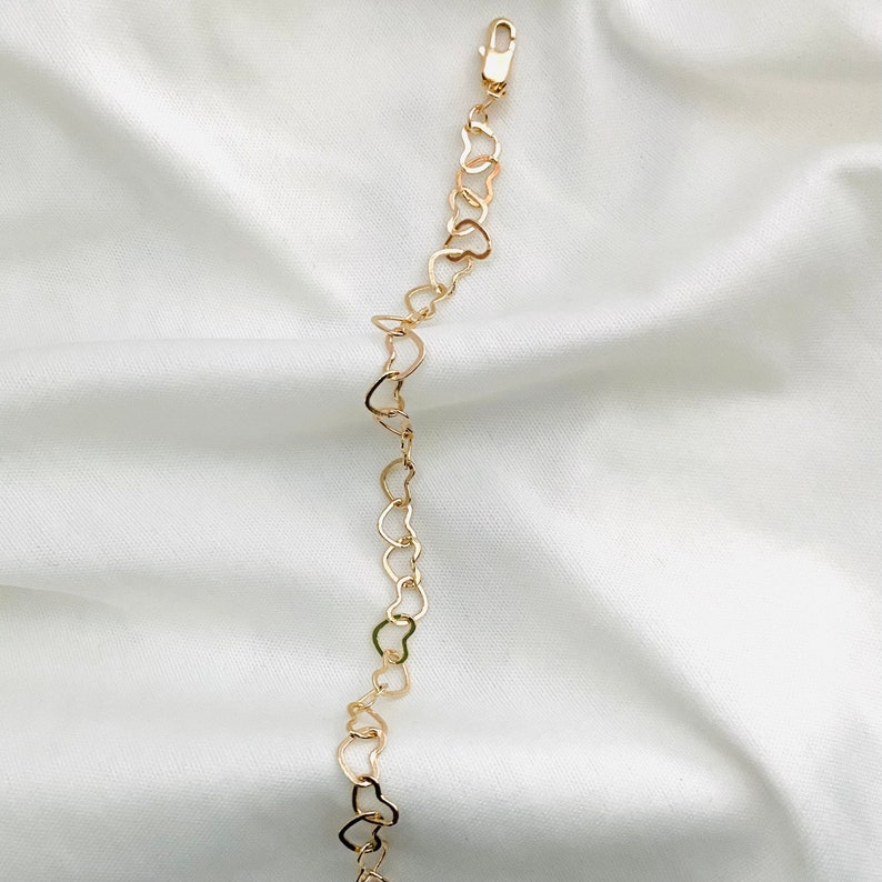 Puede incluir: Un brazalete de cadena de oro en forma de coraz&oacute;n. El brazalete est&aacute; hecho de peque&ntilde;os eslabones en forma de coraz&oacute;n interconectados.