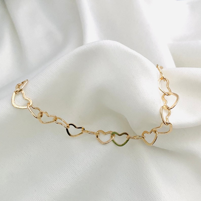 Puede incluir: Un collar de cadena de oro con un dise&ntilde;o de eslabones en forma de coraz&oacute;n.