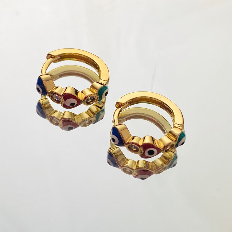 K&ouml;nnte beinhalten: Goldene Creolen mit einem Design aus mehreren blauen, roten und gr&uuml;nen b&ouml;sen Augen. Die Augen sind von kleinen klaren Strasssteinen umgeben.