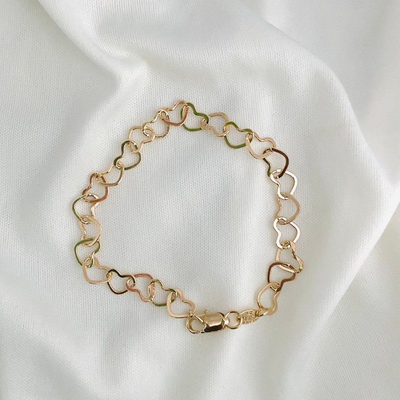 Puede incluir: Un brazalete de cadena de oro en forma de coraz&oacute;n. El brazalete est&aacute; hecho de peque&ntilde;os eslabones en forma de coraz&oacute;n interconectados.