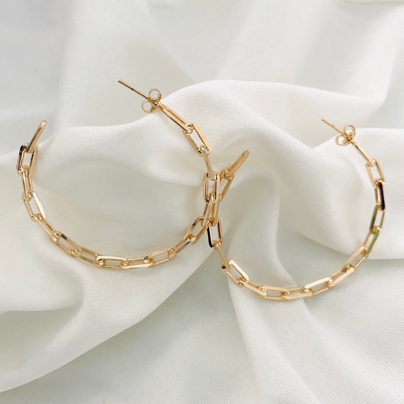 May include: Gold hoop earrings made of linked square shapes.