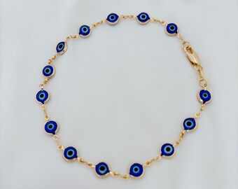Puede incluir: Un tobillo de cadena dorada con dijes de ojo azul. El tobillo está hecho de una cadena delicada y presenta múltiples dijes de ojo azul.