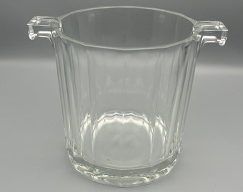 May include: A clear glass ice bucket with two handles. The bucket has a fluted design and is perfect for keeping drinks cold.